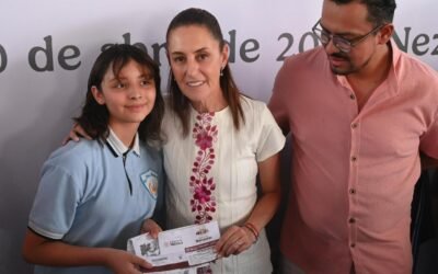 Una estudiante recibe un apoyo de la Beca Rita Cetina junto a dos adultos durante un acto oficial.