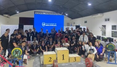 Atletas y organizadores posan junto al podio y las pesas durante el Torneo Apertura de powerlifting en Buena Esperanza.