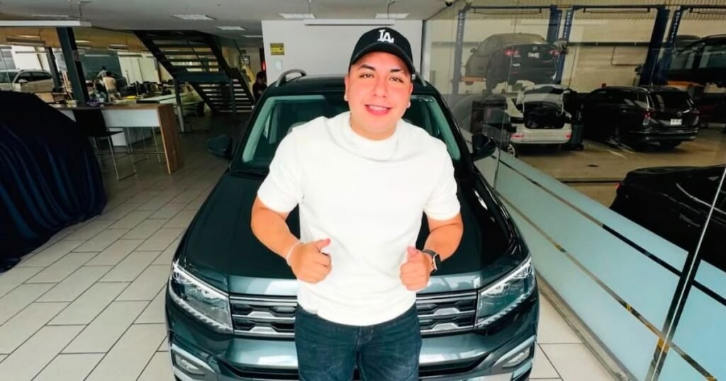Ese Pérez posa frente a un automóvil en el interior de un concesionario.