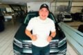 Ese Pérez posa frente a un automóvil en el interior de un concesionario.