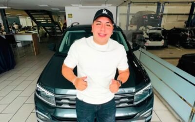 Ese Pérez posa frente a un automóvil en el interior de un concesionario.
