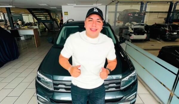 Ese Pérez posa frente a un automóvil en el interior de un concesionario.