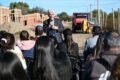 El gobernador Claudio Poggi habla ante vecinos durante una recorrida por el predio de las viviendas en construcción, con casas de ladrillo y maquinaria al fondo.