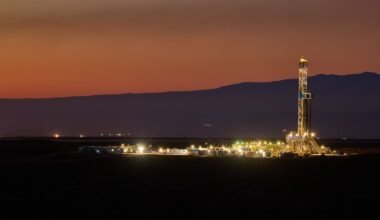 Imagen de archivo de una operación petrolera en Vaca Muerta, con una torre de perforación iluminada al atardecer.