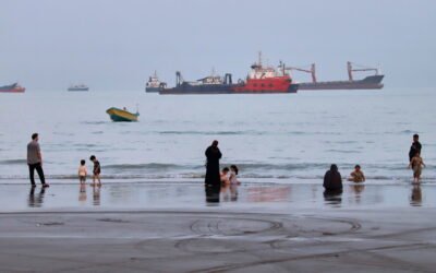 Imagen de archivo de personas en una playa frente a buques comerciales anclados en el estrecho de Ormuz, cerca de Bandar Abbas, Irán.