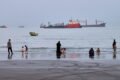 Imagen contextual de personas en una playa frente a buques anclados en el estrecho de Ormuz, cerca de Bandar Abbas, Irán.