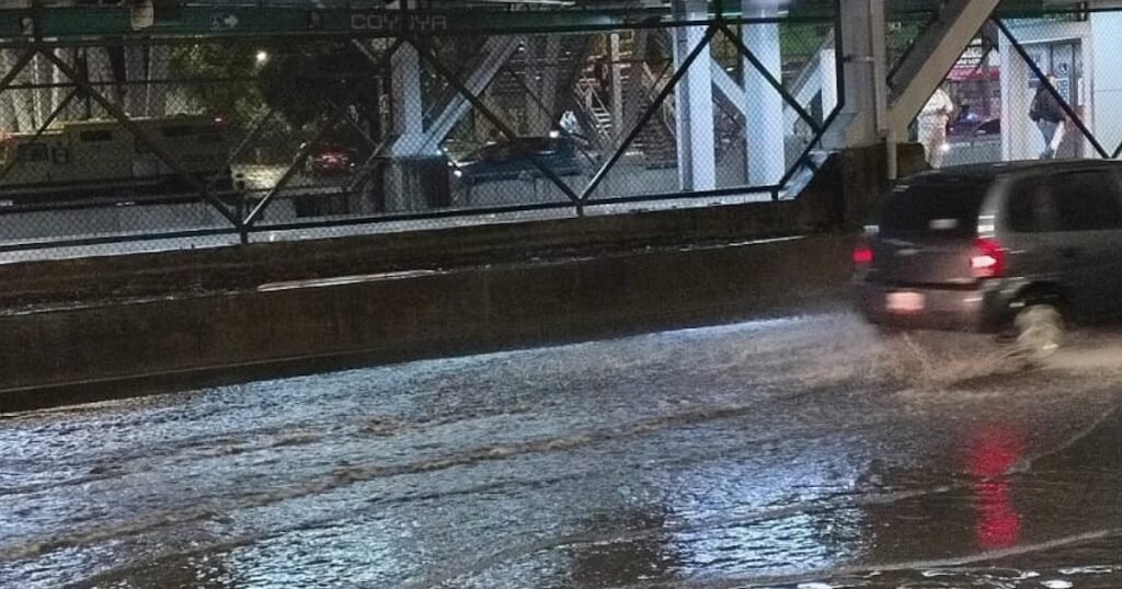 Imagen de archivo de una vía urbana anegada por la lluvia junto a infraestructura de transporte en Ciudad de México.