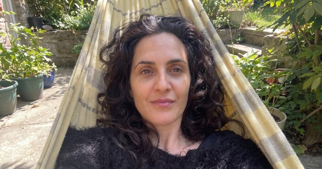 Retrato de Julieta Díaz sentada en una hamaca, en un espacio al aire libre.