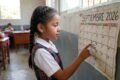 Imagen contextual de archivo: una estudiante señala un calendario escolar de septiembre de 2026 en un aula.
