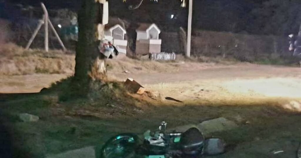 Motocicleta caída junto a un poste durante la noche, en el lugar del siniestro vial.