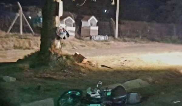 Motocicleta caída junto a un poste durante la noche, en el lugar del siniestro vial.