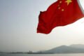 Imagen de archivo contextual de la bandera de China ondeando frente a un paisaje montañoso.