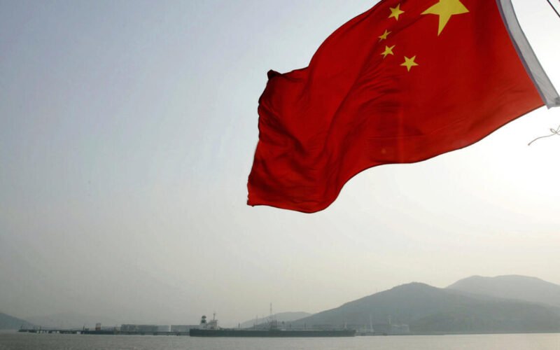Imagen de archivo contextual de la bandera de China ondeando frente a un paisaje montañoso.