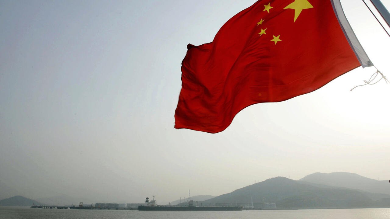 Imagen de archivo contextual de la bandera de China ondeando frente a un paisaje montañoso.