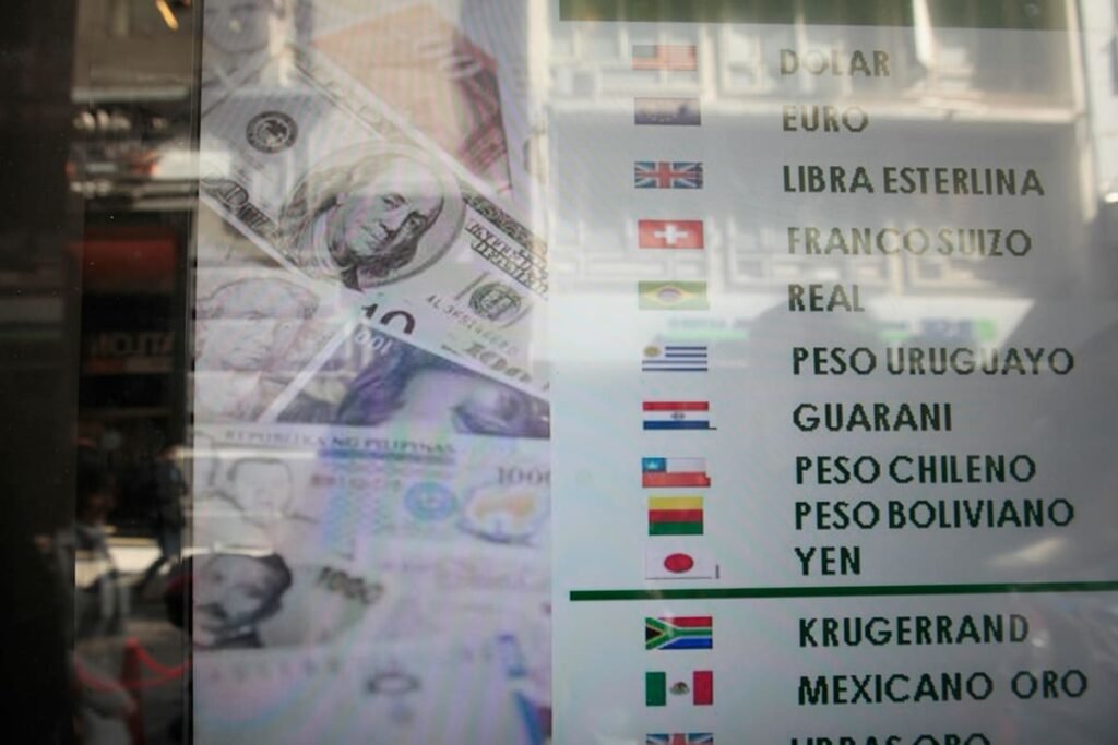 Imagen de archivo de una pizarra de cotizaciones de monedas junto a billetes de dólar.