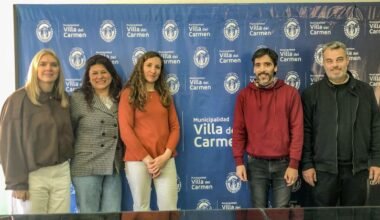 Participantes de la jornada de atención para personas con discapacidad posan frente a un panel de la Municipalidad de Villa del Carmen.