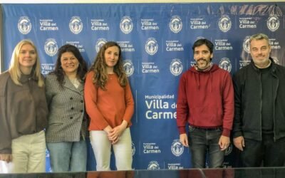 Participantes de la jornada de atención para personas con discapacidad posan frente a un panel de la Municipalidad de Villa del Carmen.