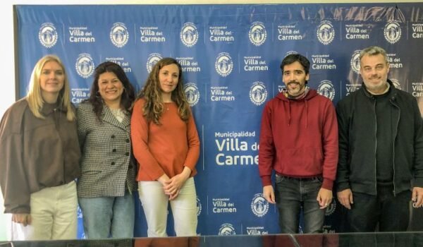 Participantes de la jornada de atención para personas con discapacidad posan frente a un panel de la Municipalidad de Villa del Carmen.