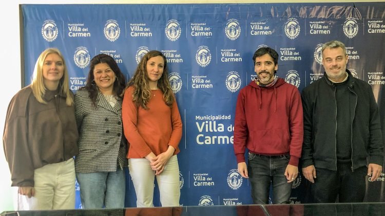 Participantes de la jornada de atención para personas con discapacidad posan frente a un panel de la Municipalidad de Villa del Carmen.