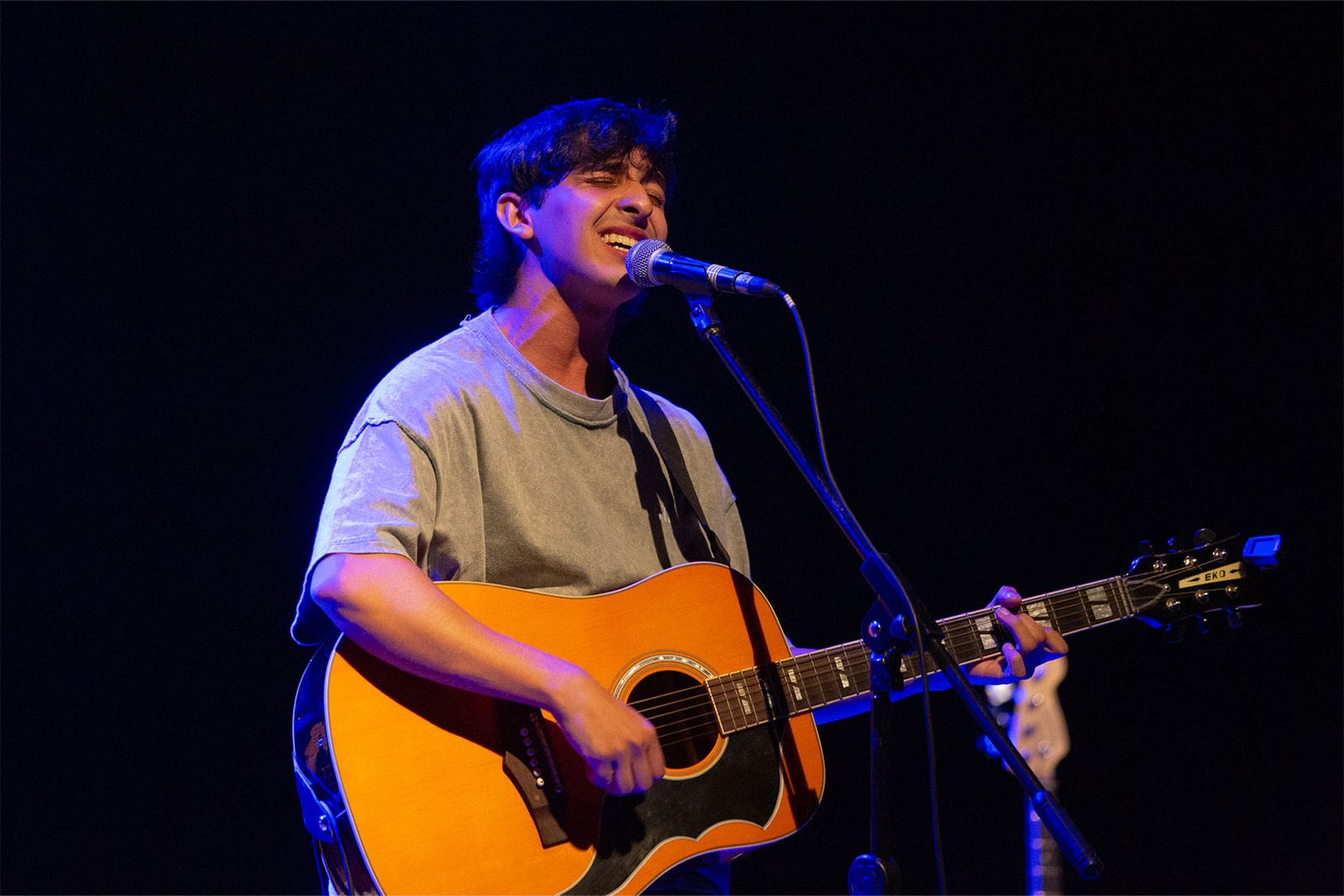 Santino Prandi canta y toca una guitarra acústica sobre el escenario