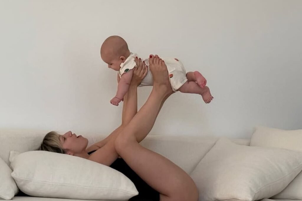 Úrsula Corberó juega con su hijo Dante en un sofá, levantándolo suavemente con las piernas.