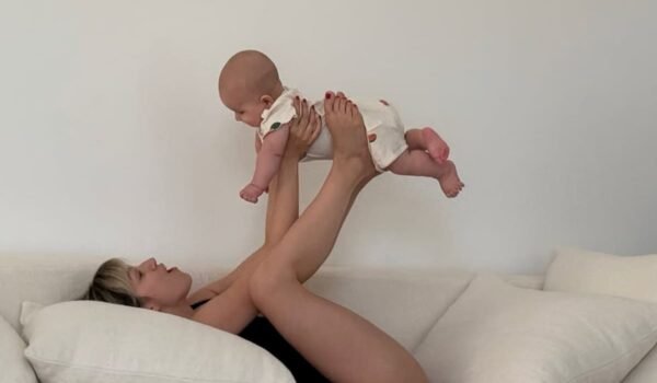 Úrsula Corberó juega con su hijo Dante en un sofá, levantándolo suavemente con las piernas.