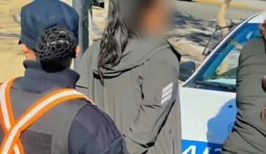 Mujer con el rostro difuminado junto a personal policial y un móvil durante el operativo en San Luis.