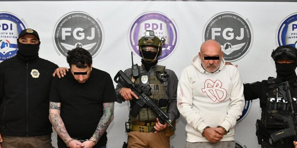 Los dos imputados permanecen bajo custodia junto a agentes de seguridad durante una presentación oficial del caso.