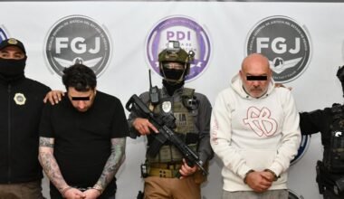 Los dos imputados permanecen bajo custodia junto a agentes de seguridad durante una presentación oficial del caso.