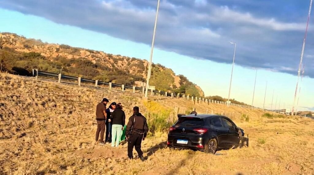 Uno de los vehículos involucrados en el choque aparece fuera de la autopista, junto a varias personas.