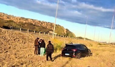 Uno de los vehículos involucrados en el choque aparece fuera de la autopista, junto a varias personas.