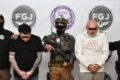Los dos imputados son escoltados por agentes frente a insignias de la Fiscalía y la Policía de Investigación.