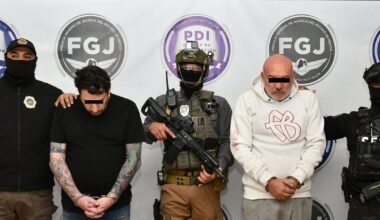 Los dos imputados son escoltados por agentes frente a insignias de la Fiscalía y la Policía de Investigación.