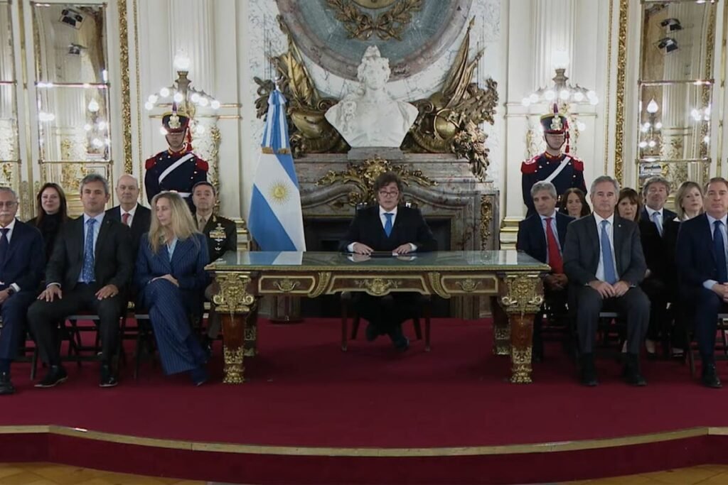 Javier Milei encabeza una cadena nacional sobre la causa Malvinas, sentado junto a funcionarios en un salón oficial.