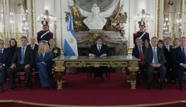 Javier Milei encabeza una cadena nacional sobre la causa Malvinas, sentado junto a funcionarios en un salón oficial.