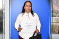 Estela Figueroa sostiene un certificado frente a una ventana.