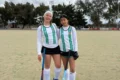 Sigrid Sackewitz y Lara Ferreyra, jugadoras del seleccionado puntano Sub 16, posan con sus palos en una cancha de hockey.