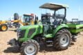 Tractor agrícola exhibido junto a otros equipos y maquinaria.