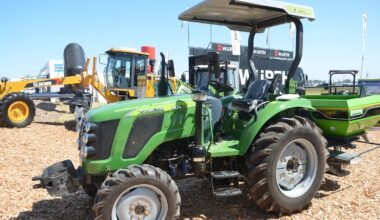 Tractor agrícola exhibido junto a otros equipos y maquinaria.