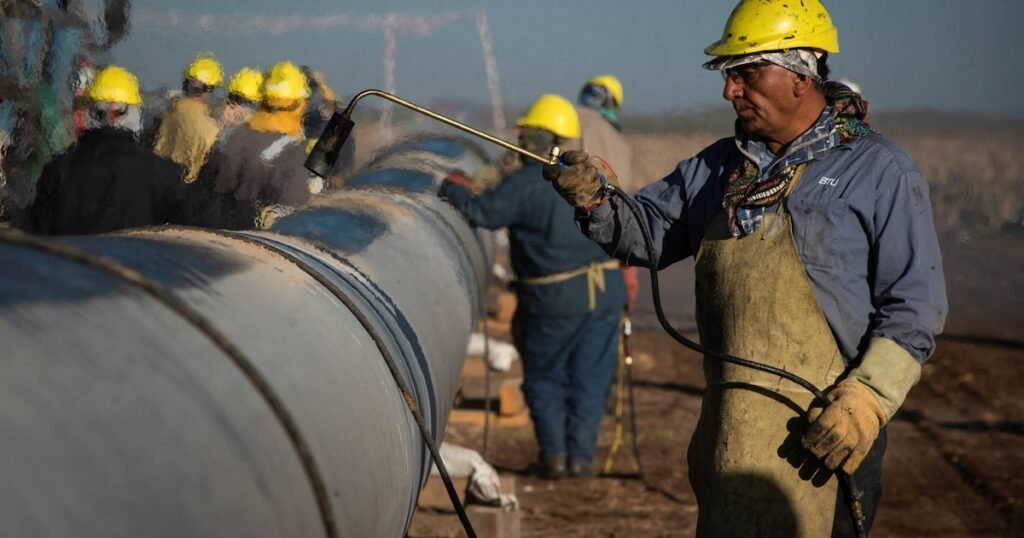 Imagen contextual de trabajadores industriales realizando tareas junto a una tubería.