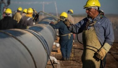 Imagen contextual de trabajadores industriales realizando tareas junto a una tubería.