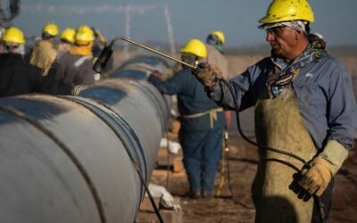 Imagen contextual de trabajadores industriales realizando tareas junto a una tubería.