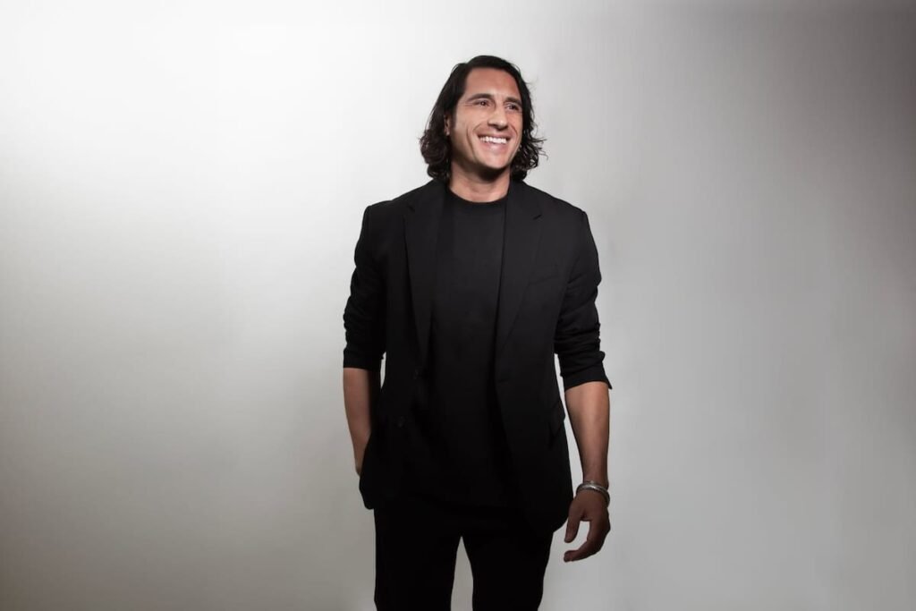 Santiago Tejedor Calvo, retratado de pie y sonriente, viste de negro sobre un fondo claro.