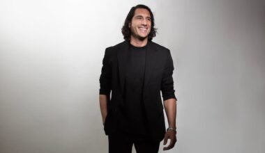 Santiago Tejedor Calvo, retratado de pie y sonriente, viste de negro sobre un fondo claro.