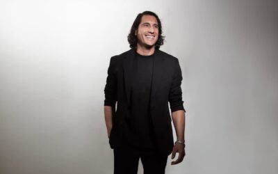 Santiago Tejedor Calvo, retratado de pie y sonriente, viste de negro sobre un fondo claro.
