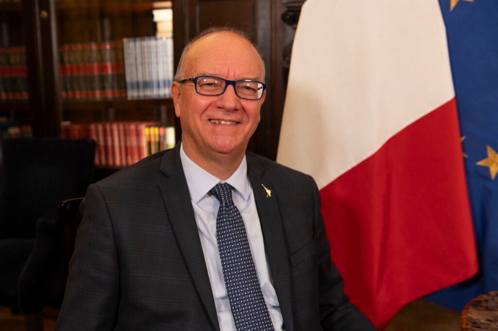 Giuseppe Valditara, ministro de Educación y Mérito de Italia, retratado junto a las banderas de Italia y la Unión Europea.