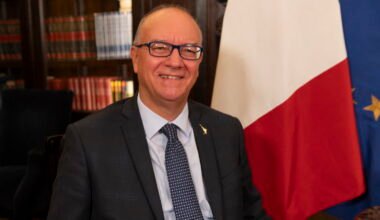 Giuseppe Valditara, ministro de Educación y Mérito de Italia, retratado junto a las banderas de Italia y la Unión Europea.