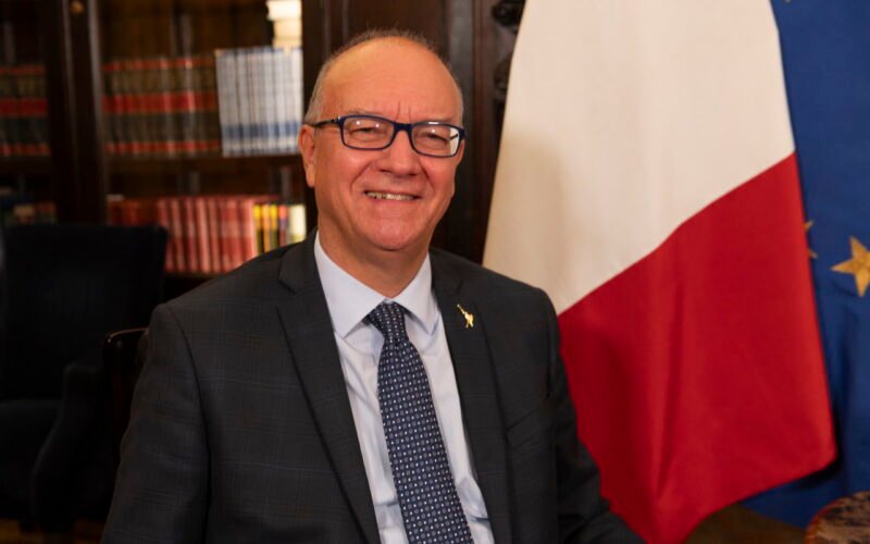 Giuseppe Valditara, ministro de Educación y Mérito de Italia, retratado junto a las banderas de Italia y la Unión Europea.