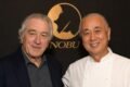 Robert De Niro y el chef Nobu Matsuhisa posan juntos frente al logo de Nobu.