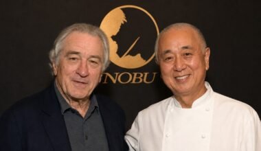 Robert De Niro y el chef Nobu Matsuhisa posan juntos frente al logo de Nobu.